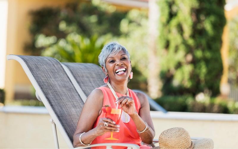 a woman sitting on a chair outside with a drink in her hand