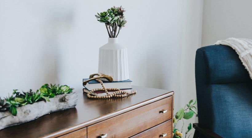 a dresser with a vase of plants on top
